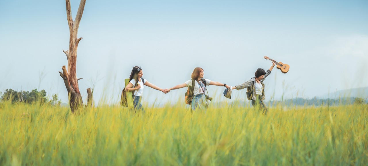 Three young women hiking together in nature. They are best friends from elementary school, Real people.
