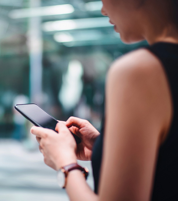 Close up of busy businesswoman emailing on mobile phone by office towers in downtown financial district