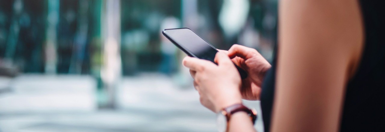 Close up of busy businesswoman emailing on mobile phone by office towers in downtown financial district