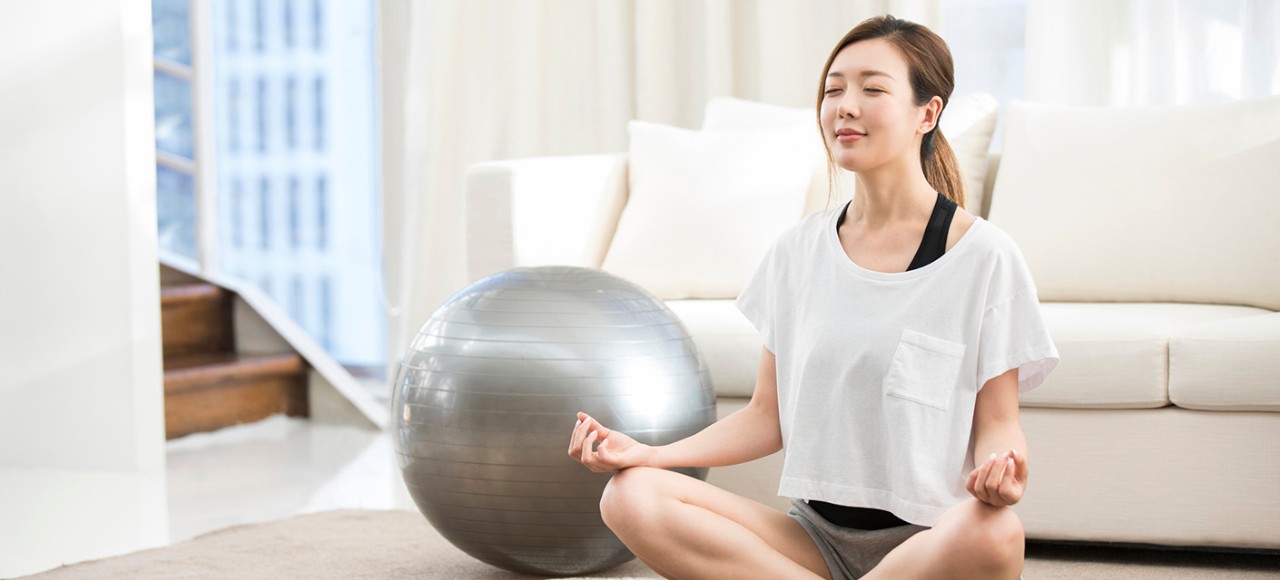 活躍的年輕亞洲運動員在家運動後休息，坐在運動墊上閉上眼睛深呼吸。體育運動和日常運動。健康、健身和保健概念